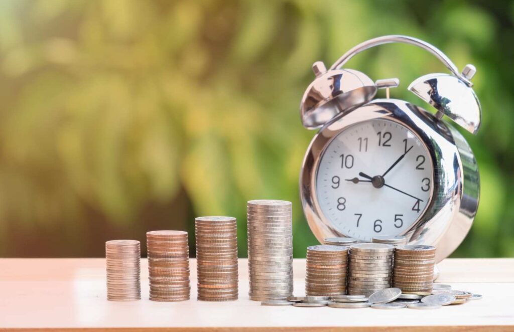 Alarm clock next to piles of coins